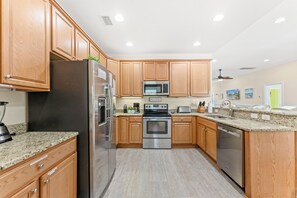 A modern kitchen with wooden cabinets, stainless steel appliances, granite countertops, and a built-in oven. - Fun In The Sun, Luxury Beach House with Pool, Blocks from Beach (North Myrtle Beach)