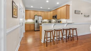 Una cocina moderna con armarios de madera, un refrigerador de acero inoxidable y una encimera de granito.