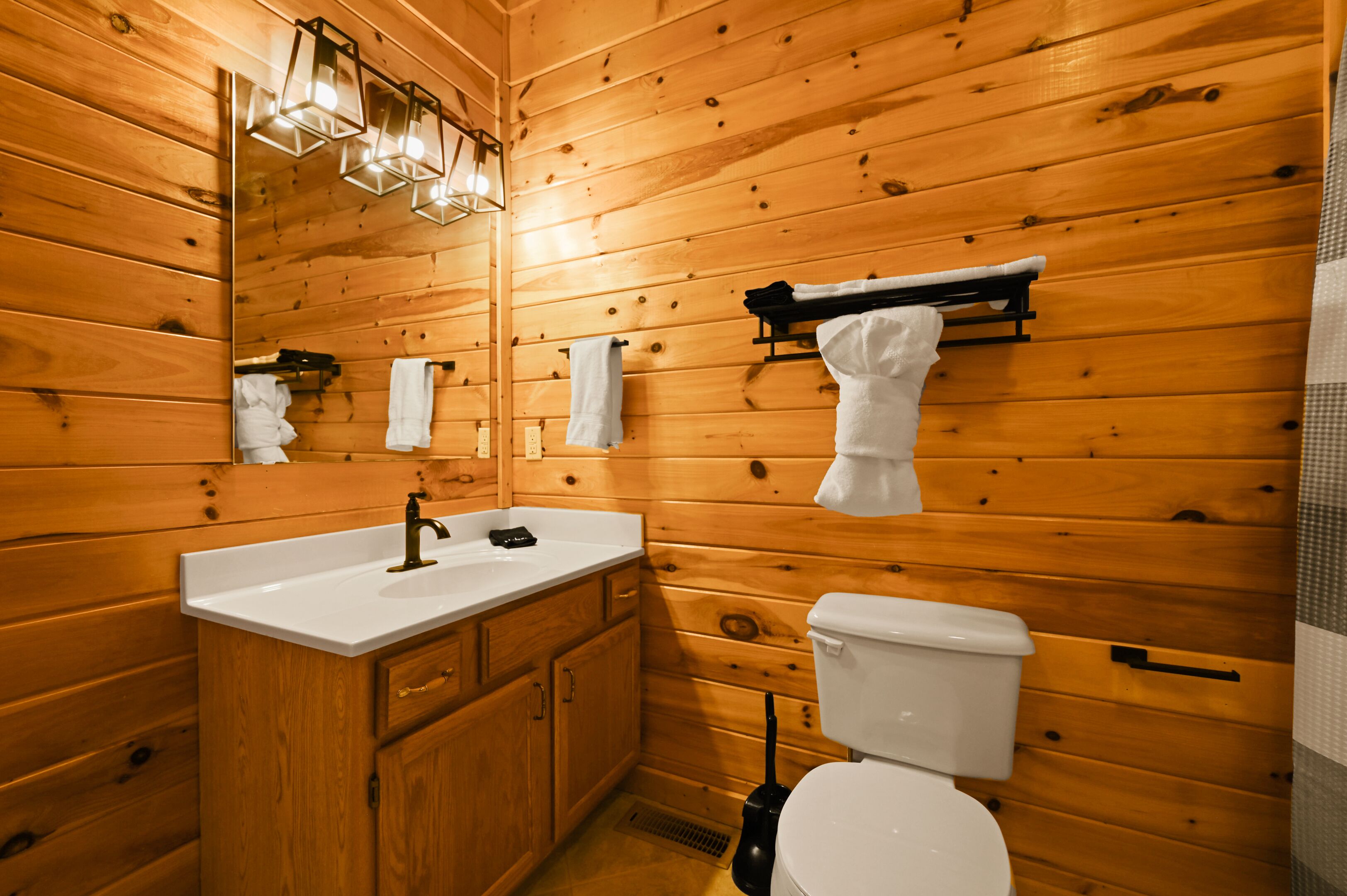 Un baño con paneles de madera, un lavabo, un espejo y un inodoro.