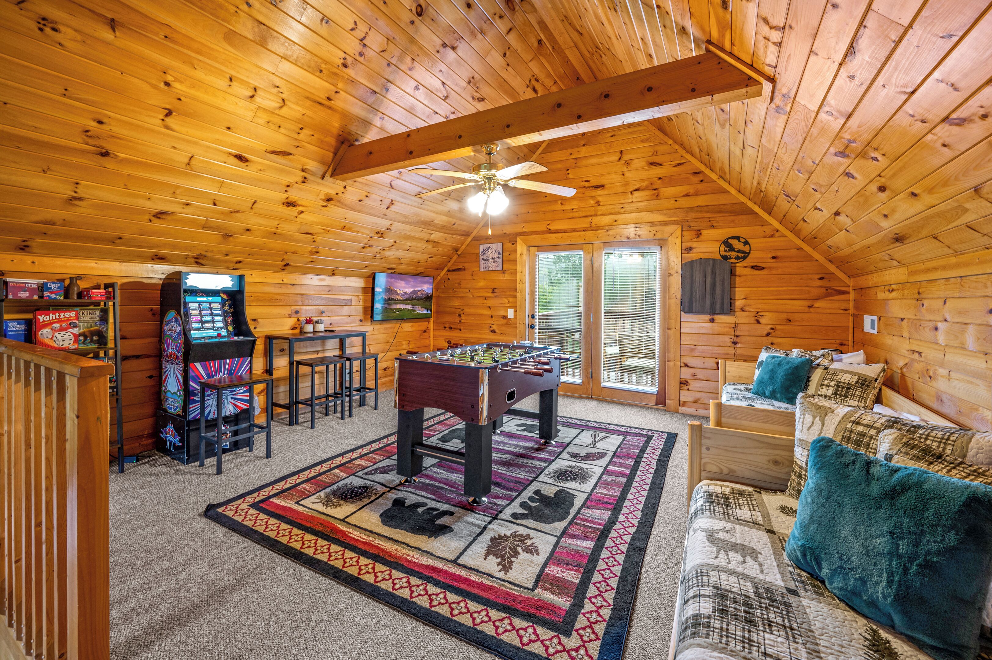 Un intérieur chaleureux de chalet en bois, avec une table de baby-foot, un téléviseur et un coin bar.