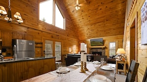 Una cabaña de madera con cocina, comedor y chimenea.