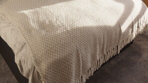 Quarto com uma cama grande, mesa de cabeceira, abajur e janela com cortinas.
