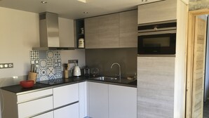 Uma cozinha moderna com armários brancos, bancada preta e forno embutido.