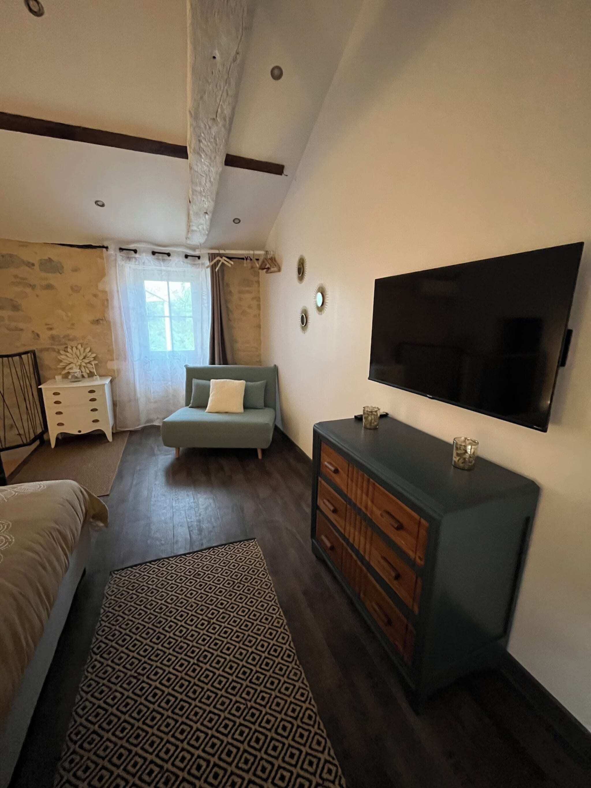 Ein Schlafzimmer mit Bett, Sofa, Fernseher und Kommode.
