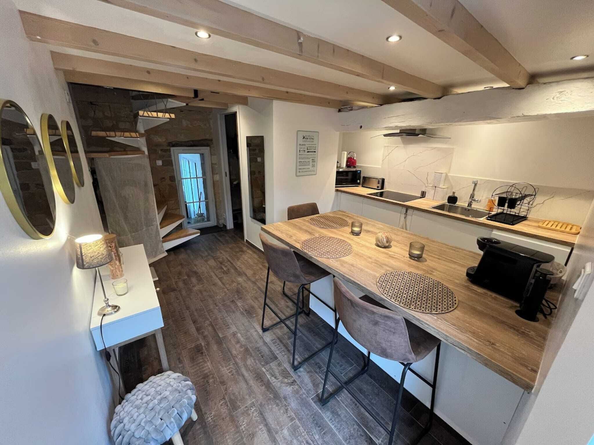 A modern kitchen with wooden countertops, a dining area with a wooden table and chairs, and a visible staircase leading to another level.