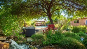 Um quintal com piscina, móveis de jardim e uma cascata.
