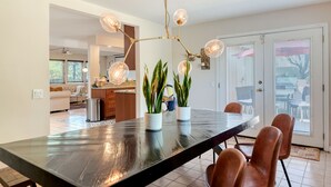 Uma cozinha moderna com uma ilha central, iluminação pendente e plantas em vasos.