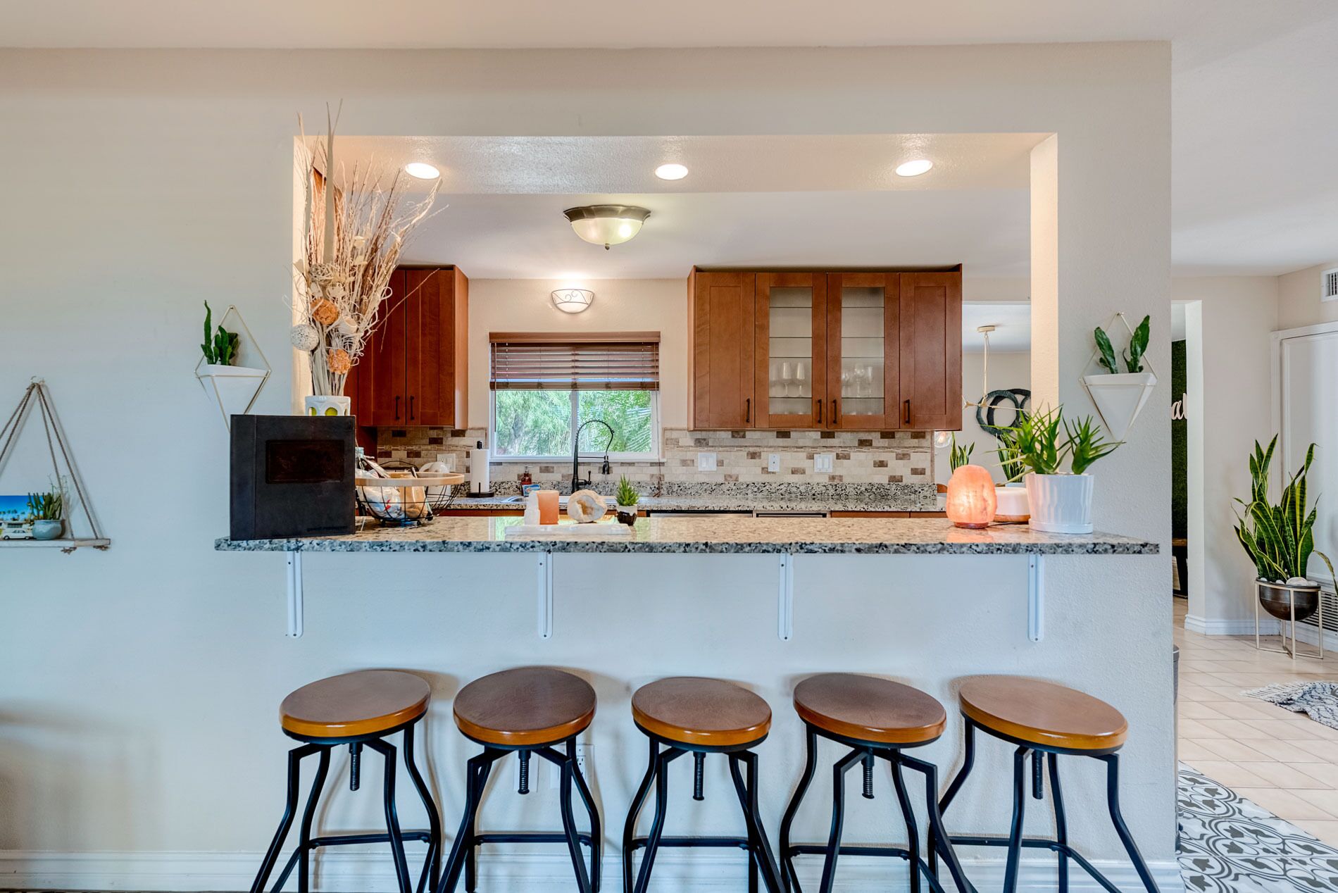 A modern kitchen with wooden cabinets, a granite countertop, and bar stools.