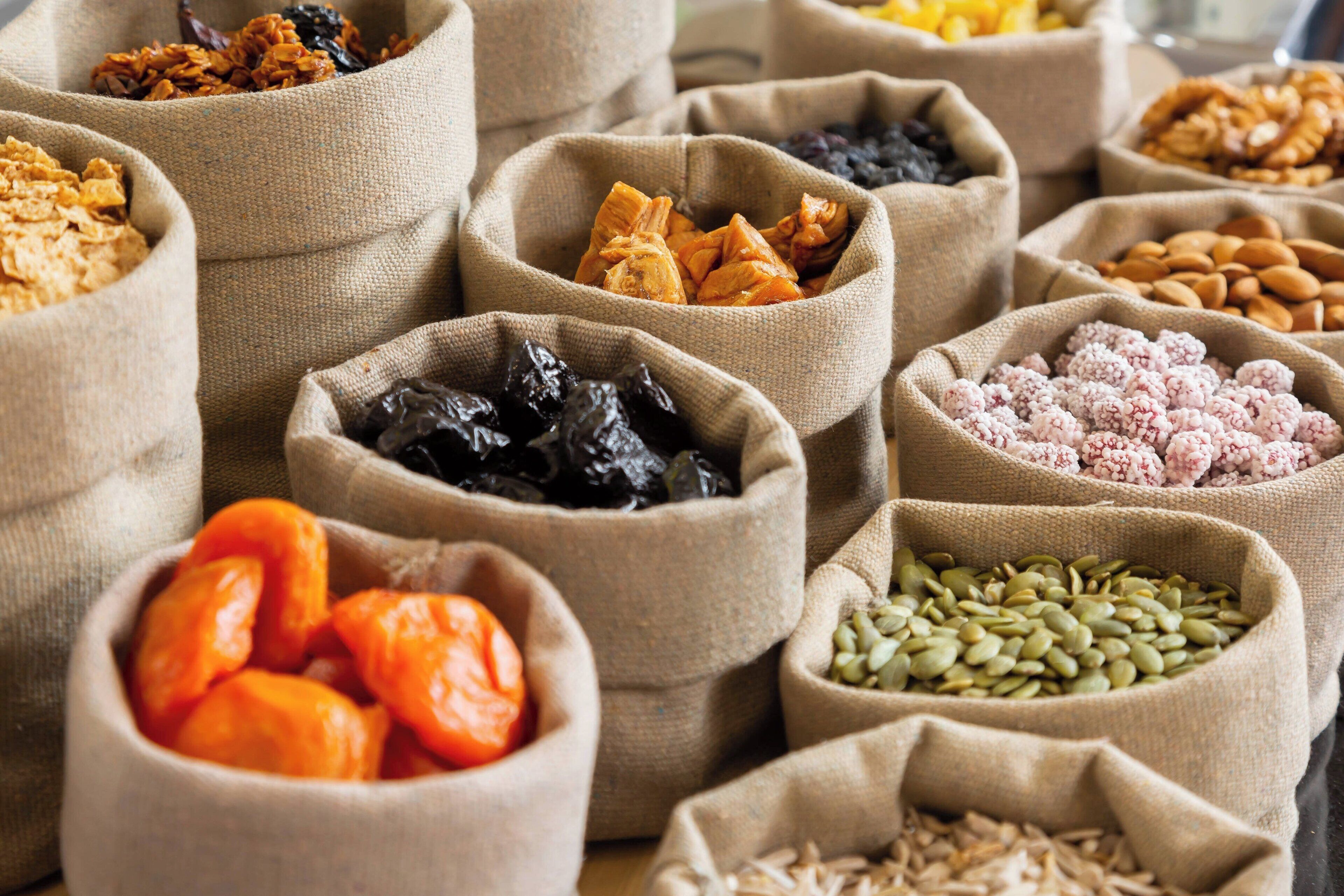 Multiple burlap sacks filled with various dried fruits and nuts.