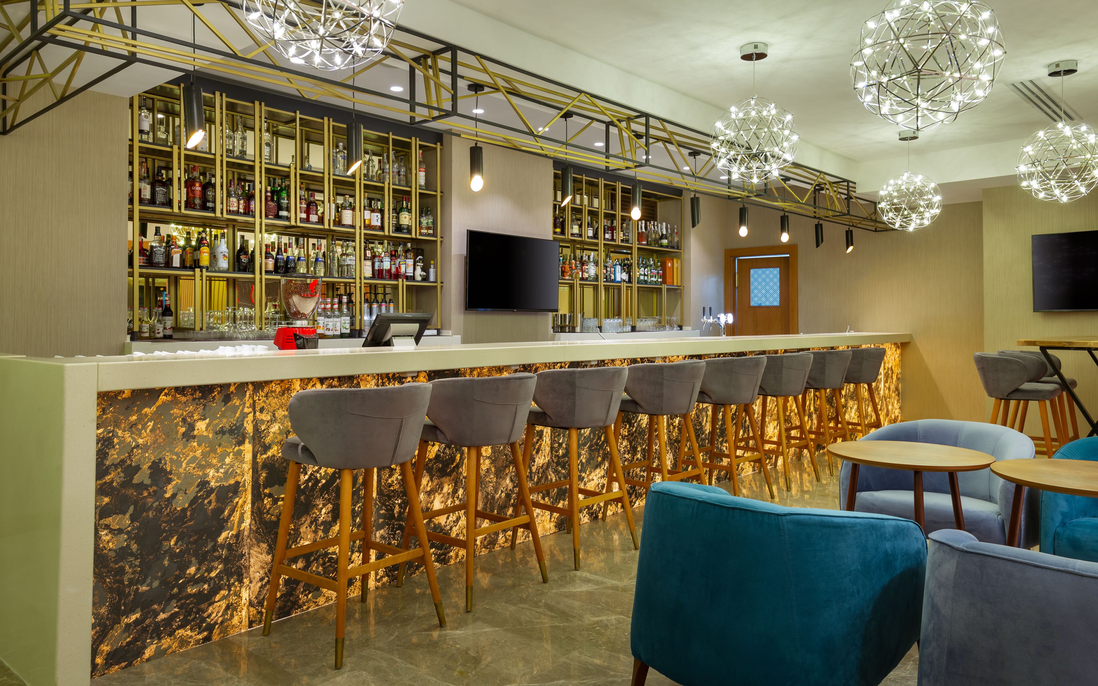 Eine Bar mit einer Marmorplatte, Barhocker und einer Sitzecke mit runden Tischen und Stühlen.