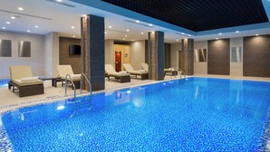 An indoor swimming pool with lounge chairs and a tiled ceiling. - Courtyard by Marriott Tashkent (Tashkent)