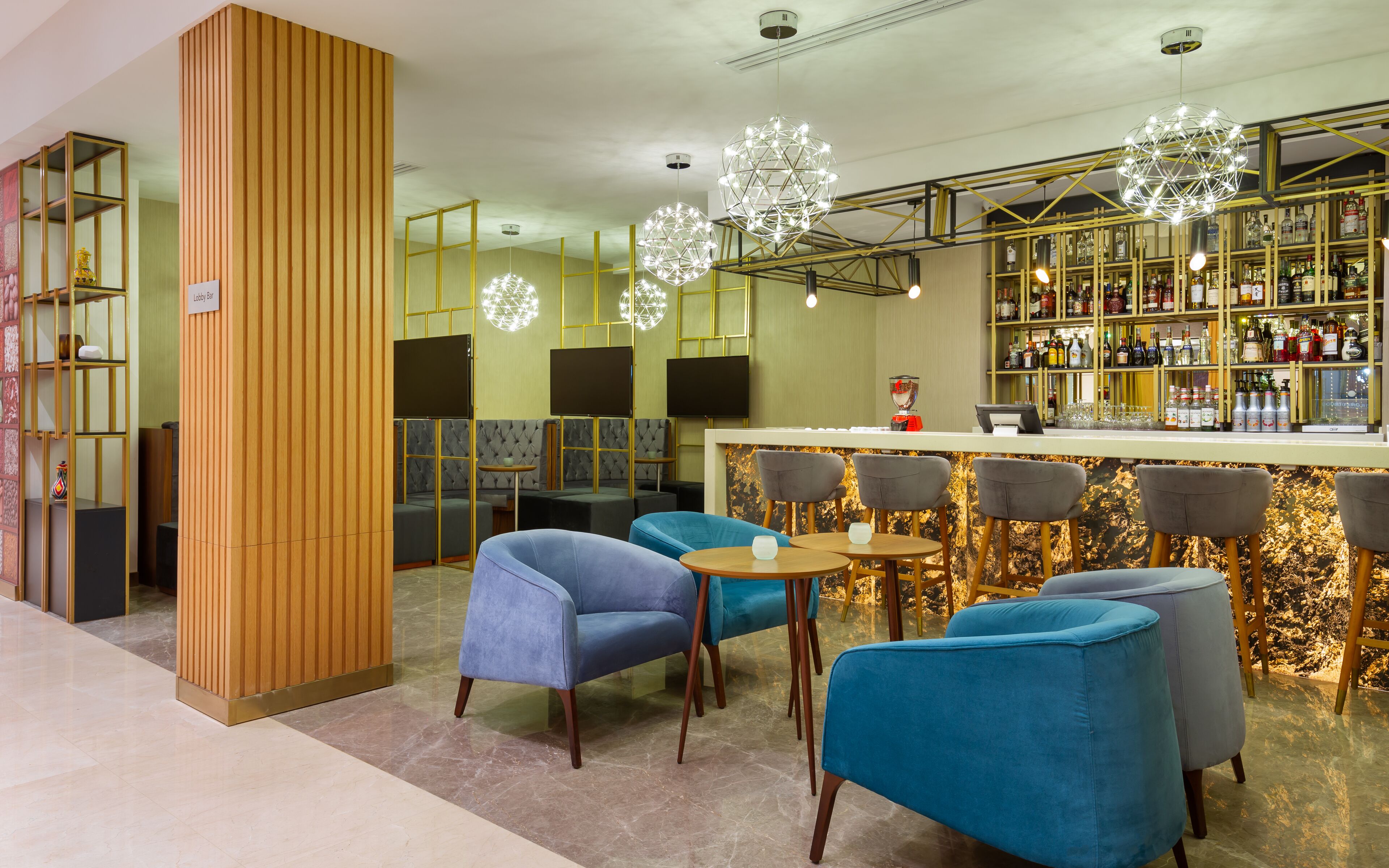 A bar area with blue chairs, a counter with a cash register, and shelves of liquor bottles.