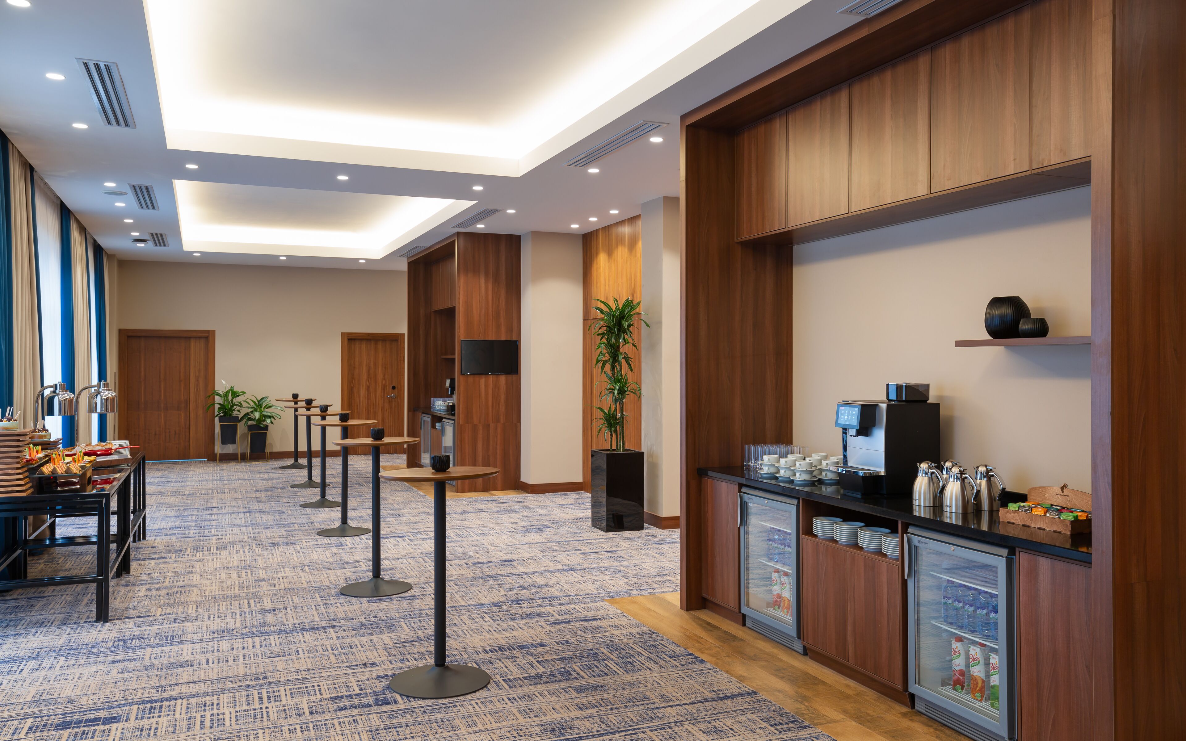 A hotel lobby with a reception area, a buffet setup, and a coffee station.