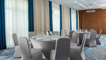 A conference room with round tables, white chairs, and a blue and beige color scheme.