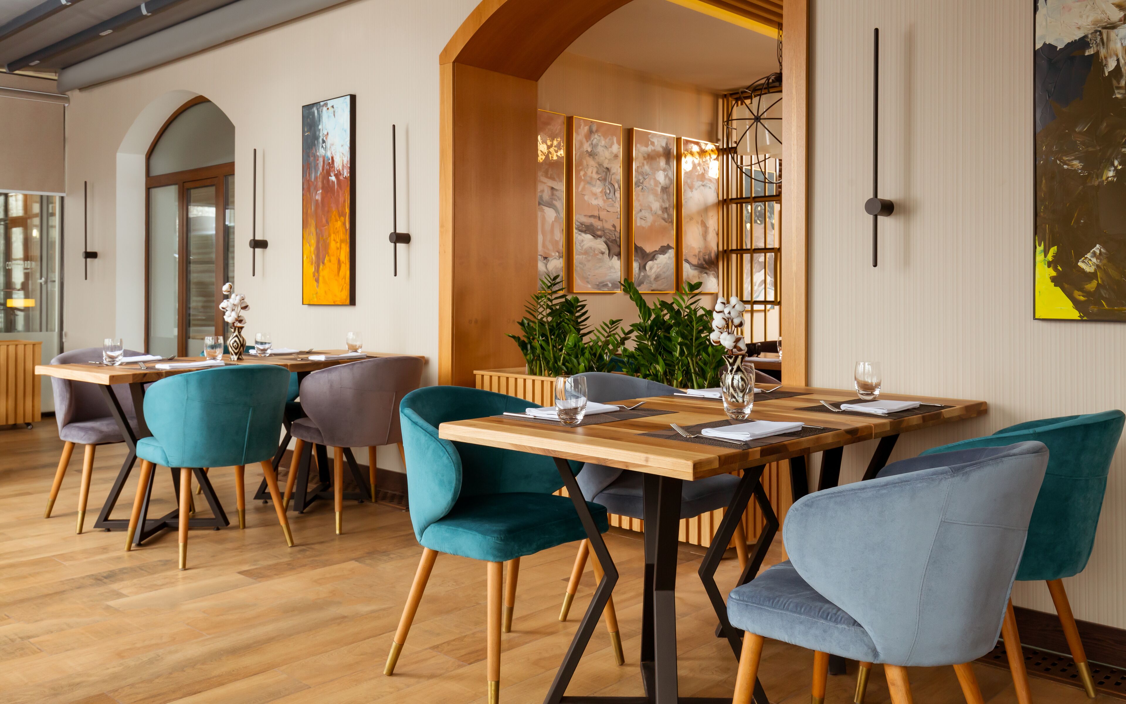 A modern dining area with wooden tables and teal chairs.