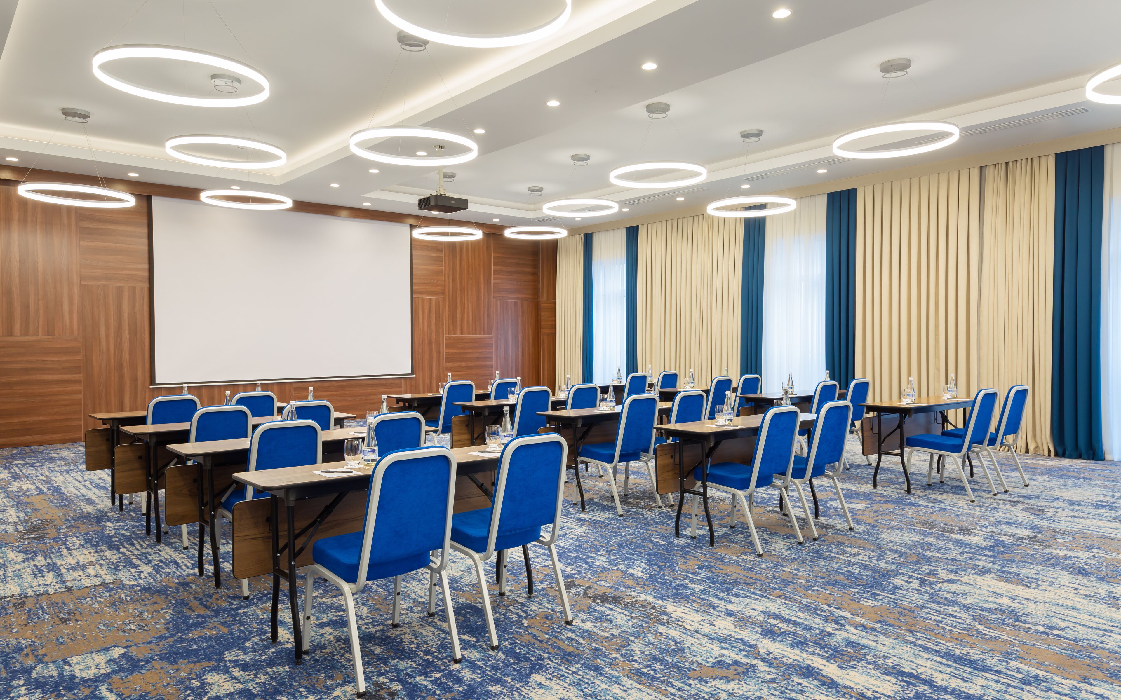 A conference room with a whiteboard, blue chairs, and a carpeted floor.