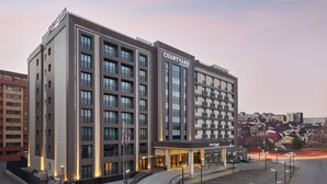 A Courtyard by Marriott hotel with a modern design, featuring multiple floors, large windows, and a parking area. - Courtyard by Marriott Tashkent (Tashkent)