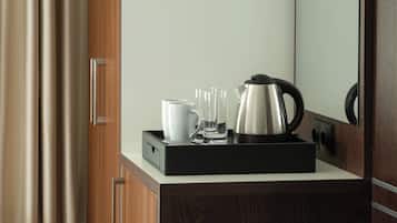 Un área de cocina moderna con cafetera, hervidor y bandeja.