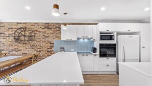 Una cocina moderna con armarios blancos, una pared de ladrillo decorativa y una isla grande.