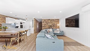 Un espacio habitable moderno con cocina, comedor y una zona de estar acogedora con sofá y cojines.