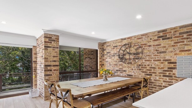 Un comedor con una mesa de madera, bancos y una pared de ladrillo.