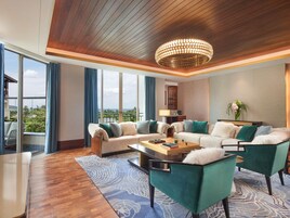 Ein modernes Wohnzimmer mit Holzboden, einer großen Kronleuchter, einer Sofagarnitur, einem Couchtisch und Blick ins Freie.