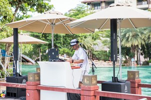 Ein DJ-Pult mit Tontechnik und Sonnenschirmen an einer Veranstaltungslocation am Wasser.