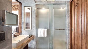 A modern bathroom with a marble sink, a glass-enclosed shower, and a wooden vanity.