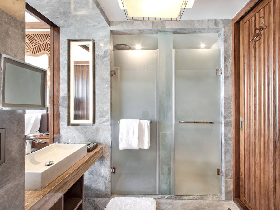 A modern bathroom with a marble sink, a glass-enclosed shower, and a wooden vanity.