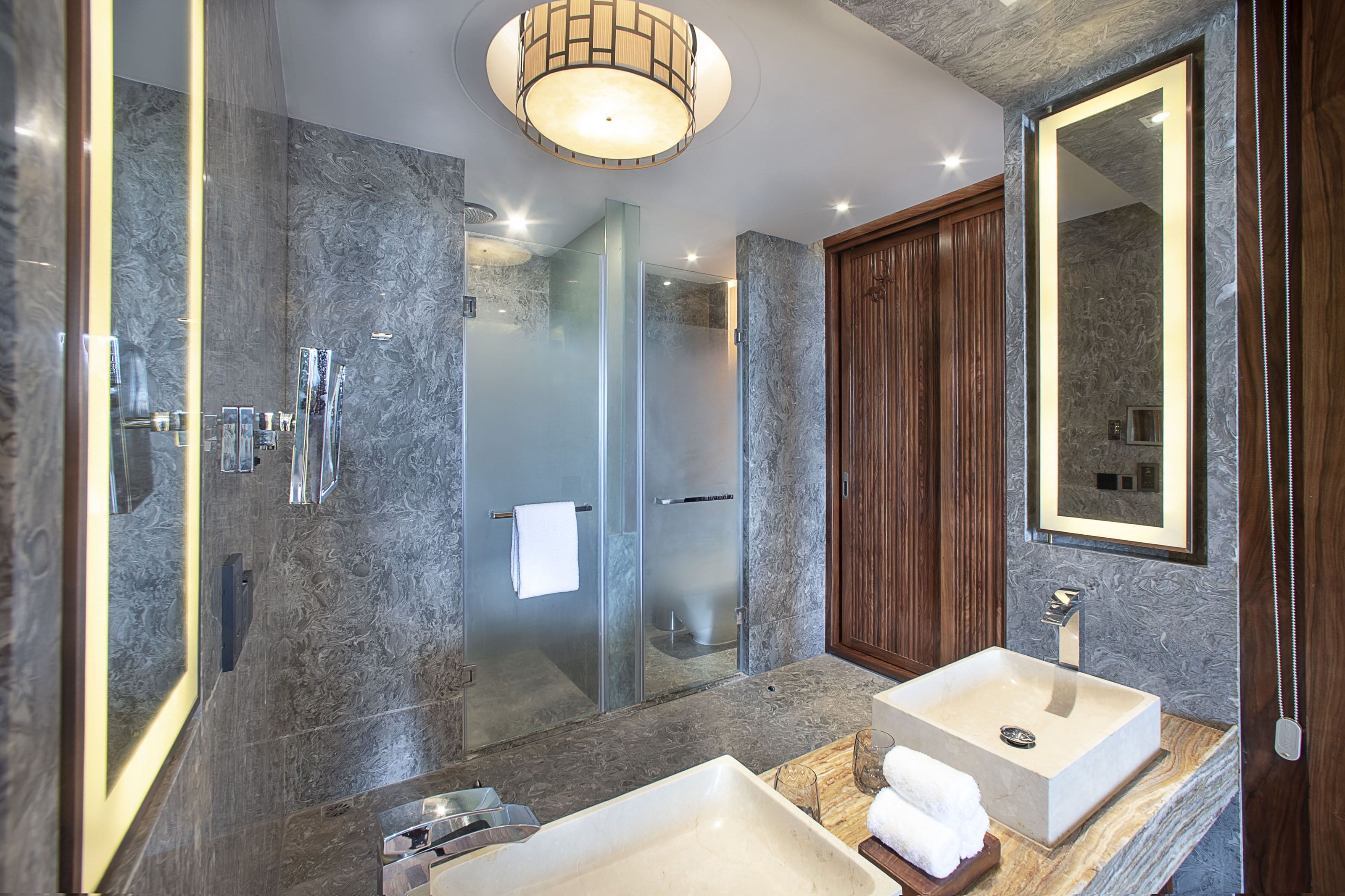 Ein modernes Badezimmer mit einer Duschkabine, zwei Waschbecken und einem großen Spiegel.