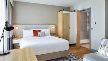 Une chambre d’hôtel moderne, dotée d’un grand lit, de tables de chevet, d’un bureau et d’une chaise.