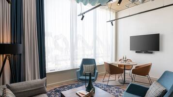 Una sala de estar moderna con un sofá, sillones, una mesa de centro y un televisor montado en la pared.