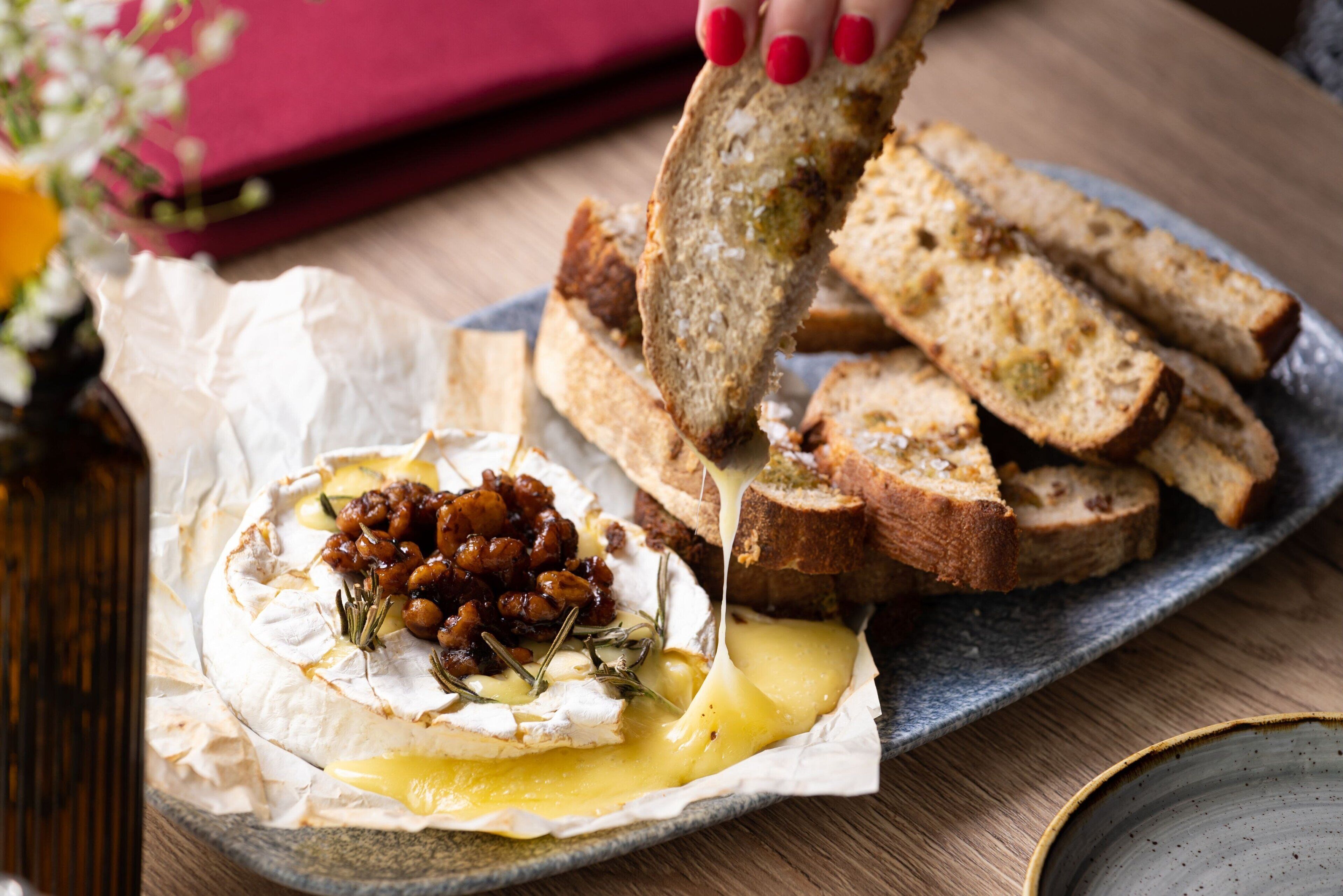 Una tabla de fiambres con queso, pan y frutos secos sobre un plato.