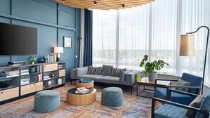 Una sala de estar moderna con un sofá gris, sillones azules, una mesa de centro y una estantería.