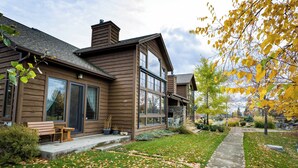 A wooden house with large windows, a front porch, and a pathway. - Luxury Bigfork Retreat | Pond Views, Stone Fireplace & Steps from Flathead Lake | 30-Day Minimum (Bigfork)