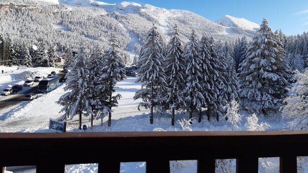Eine verschneite Berglandschaft mit schneebedeckten Bäumen und blauem Himmel.