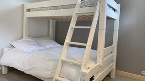 Ein Stockbett mit einer Leiter, weißer Bettwäsche und einer grauen Wand.