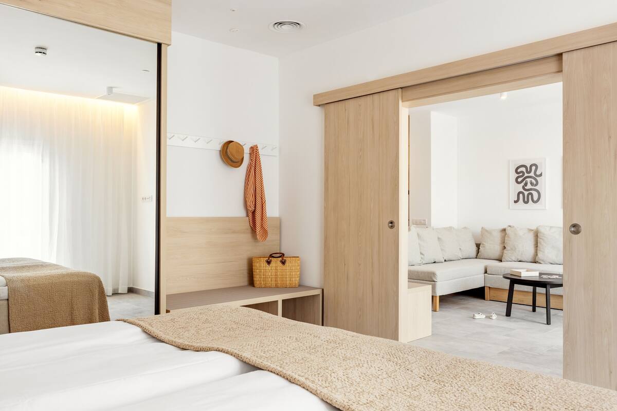 Un dormitorio moderno con cama, mesita de noche y vistas a un salón con sofá y mesa de centro.