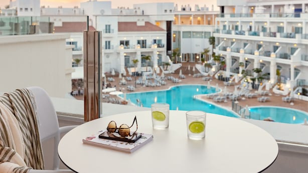 Un balcon donnant sur une piscine et les bâtiments de l’hôtel.
