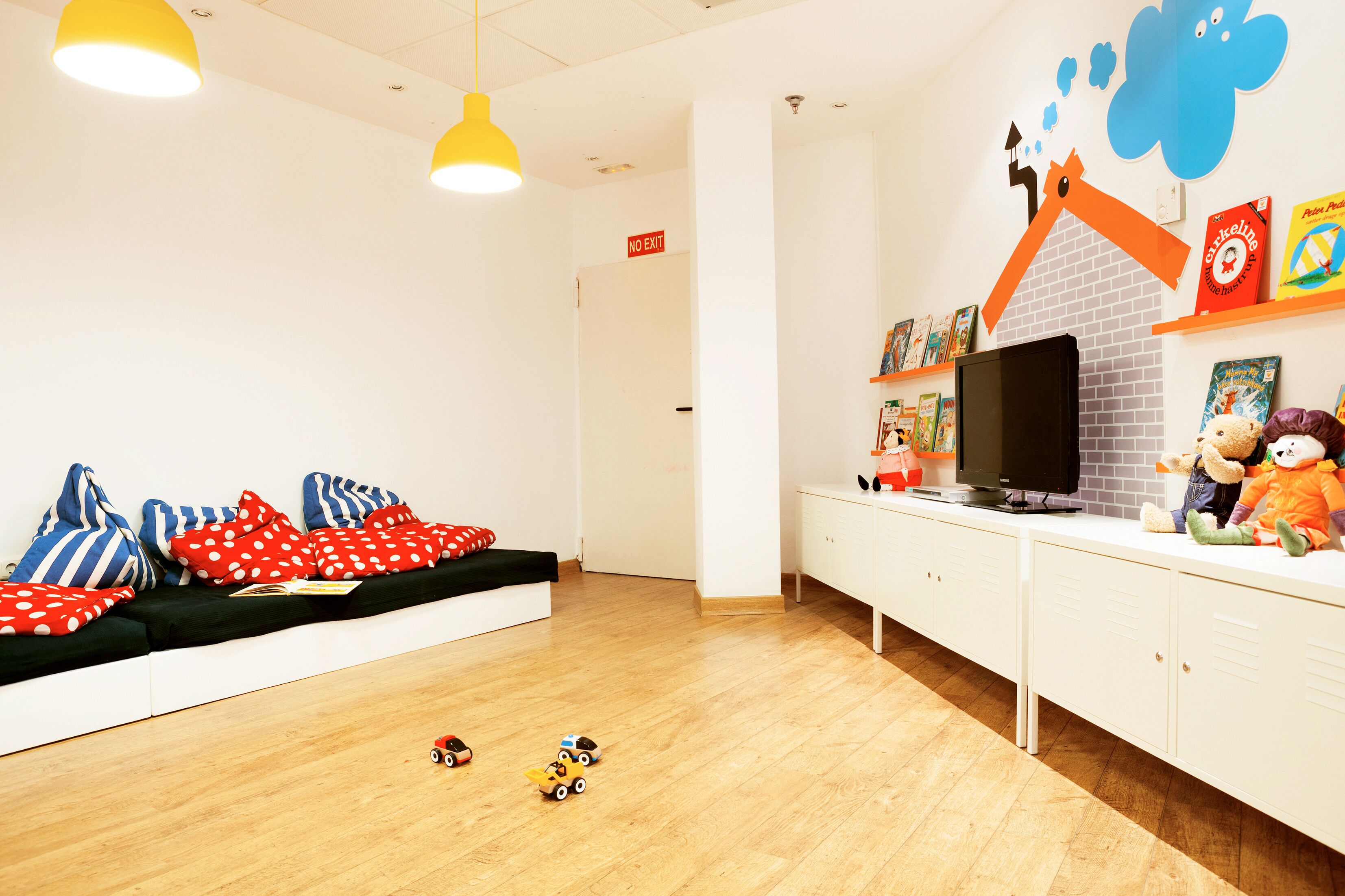 A children's play area with a sofa, toys, a television, and a brick wall decoration.