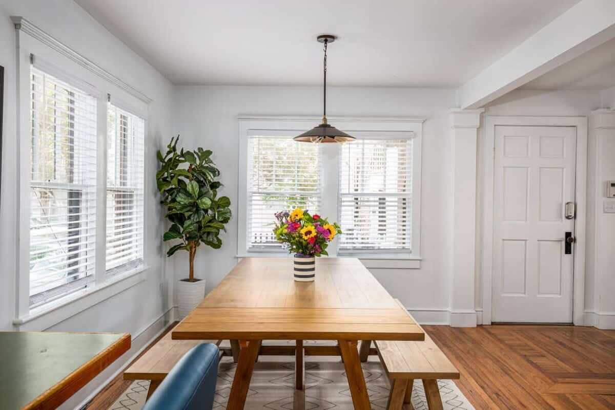 A dining area with a wooden table, benches, and a vase of flowers.
