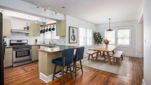 Une cuisine moderne dotée d’un îlot central, de revêtements de sol en bois et d’un coin repas avec une banquette et une table.