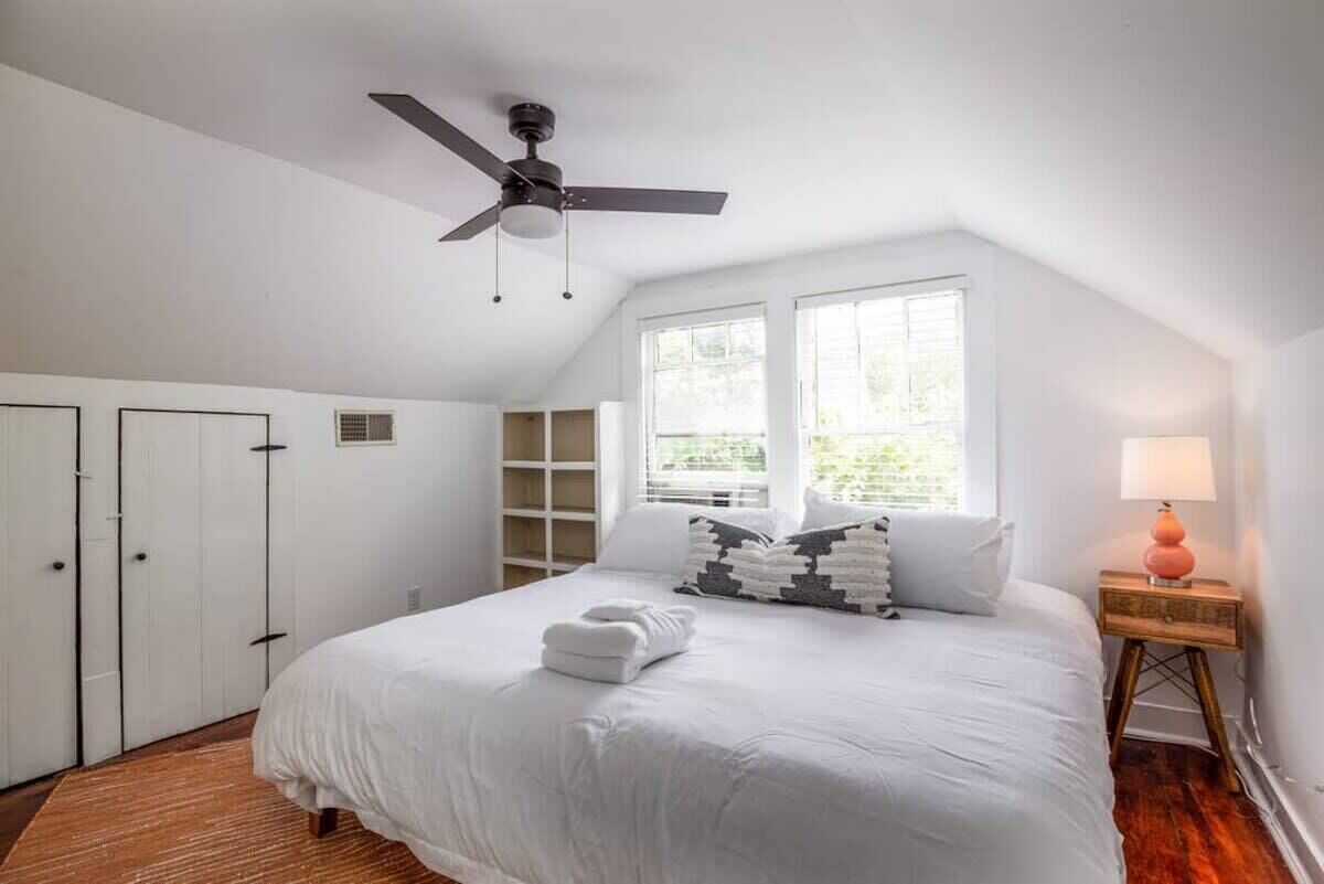 Una camera da letto con un letto, una ventola a soffitto, una finestra e un comodino.