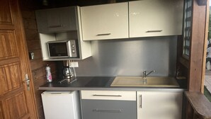 A compact kitchen with a built-in microwave, a sink, and a small refrigerator. - Bungalow Flamboyant (Bouillante)