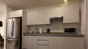 A modern kitchen with white cabinets, stainless steel appliances, and a microwave.