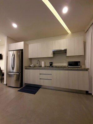 Una cocina moderna con armarios blancos, electrodomésticos de acero inoxidable y un microondas.