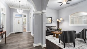 A spacious living room with a dark sofa, a wooden coffee table, and striped chairs.