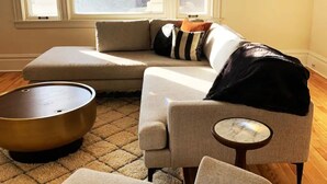 A living room with a sectional sofa, a round coffee table, and a small side table.