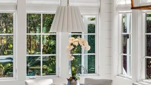 A room with a round table, chairs, a hanging light fixture, and large windows with a view of greenery. - WaterColor - 4+BR, Private Heated Pool, 6 Seat LSV - 6 Bikes (Santa Rosa Beach)