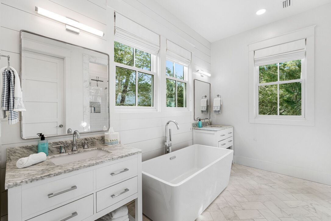 A modern bathroom with a large bathtub, two sinks, and a large mirror.